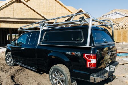 Passenger-side view of a Ford F-150 with a polished aluminum rack installed over the camper shell.