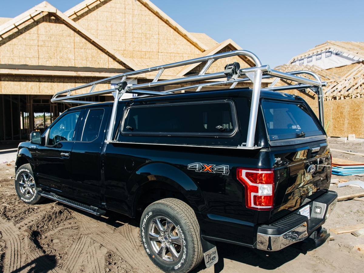 Passenger-side view of a Ford F-150 with a polished aluminum rack installed over the camper shell.