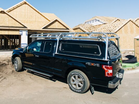 Polished aluminum camper shell ladder rack mounted over a Ford F-150 topper.
