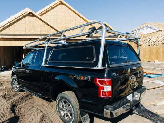 Rear-side angle of a Ford F-150 featuring a welded aluminum camper shell ladder rack.