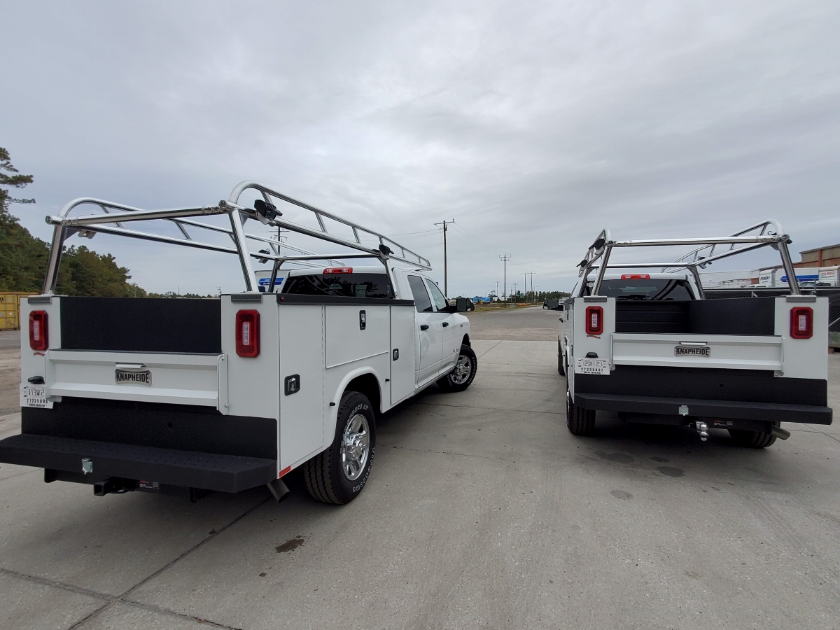 Two Ram service trucks parked side by side with polished aluminum racks.
