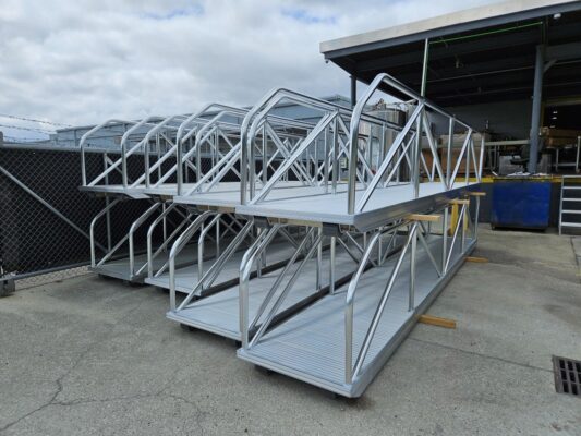 Close‑up view of custom aluminum gangways stacked for bulk order, showing handrails and non‑slip decks