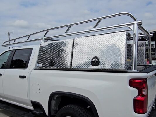 Rear angled view of the anodized aluminum ladder rack with tool boxes mounted above the bed rails.