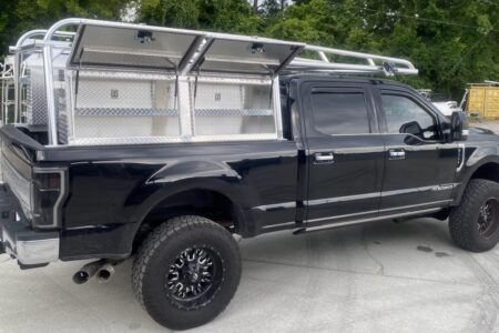 Rear-corner perspective showing Ryder Rack WELD with six High Speed Rack Straps and additional over-cab bar on a Ford F-250.