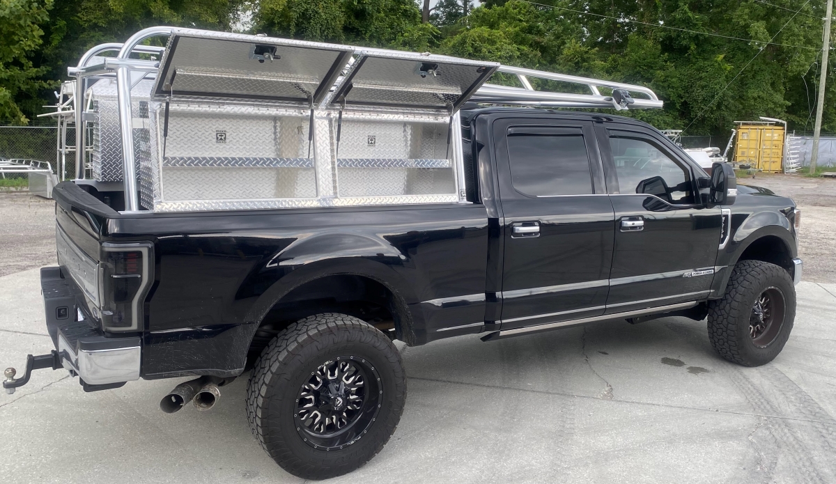 Rear-corner perspective showing Ryder Rack WELD with six High Speed Rack Straps and additional over-cab bar on a Ford F-250.