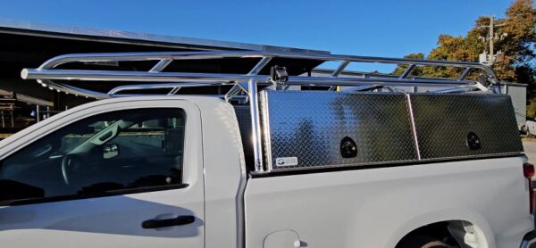 Driver side view of white Chevy pickup with Ryder Rack WELD ladder rack and diamond‑plate topsider toolboxes