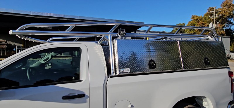 Driver side view of white Chevy pickup with Ryder Rack WELD ladder rack and diamond-plate topsider toolboxes