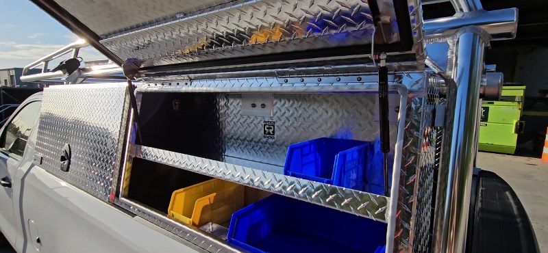 Open topsider toolbox showing gas-strut lid, diamond-plate interior and color-coded storage bins