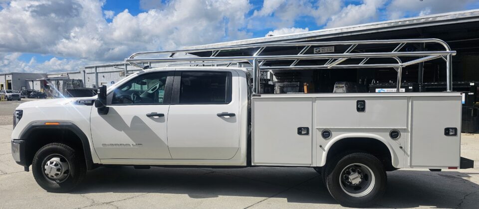 Full side profile of a GMC Sierra HD with a Knapheide service body and welded aluminum Ryder Rack ladder rack.