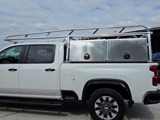 Side view of the anodized aluminum ladder rack with tool boxes installed on a Chevy 2500 HD.