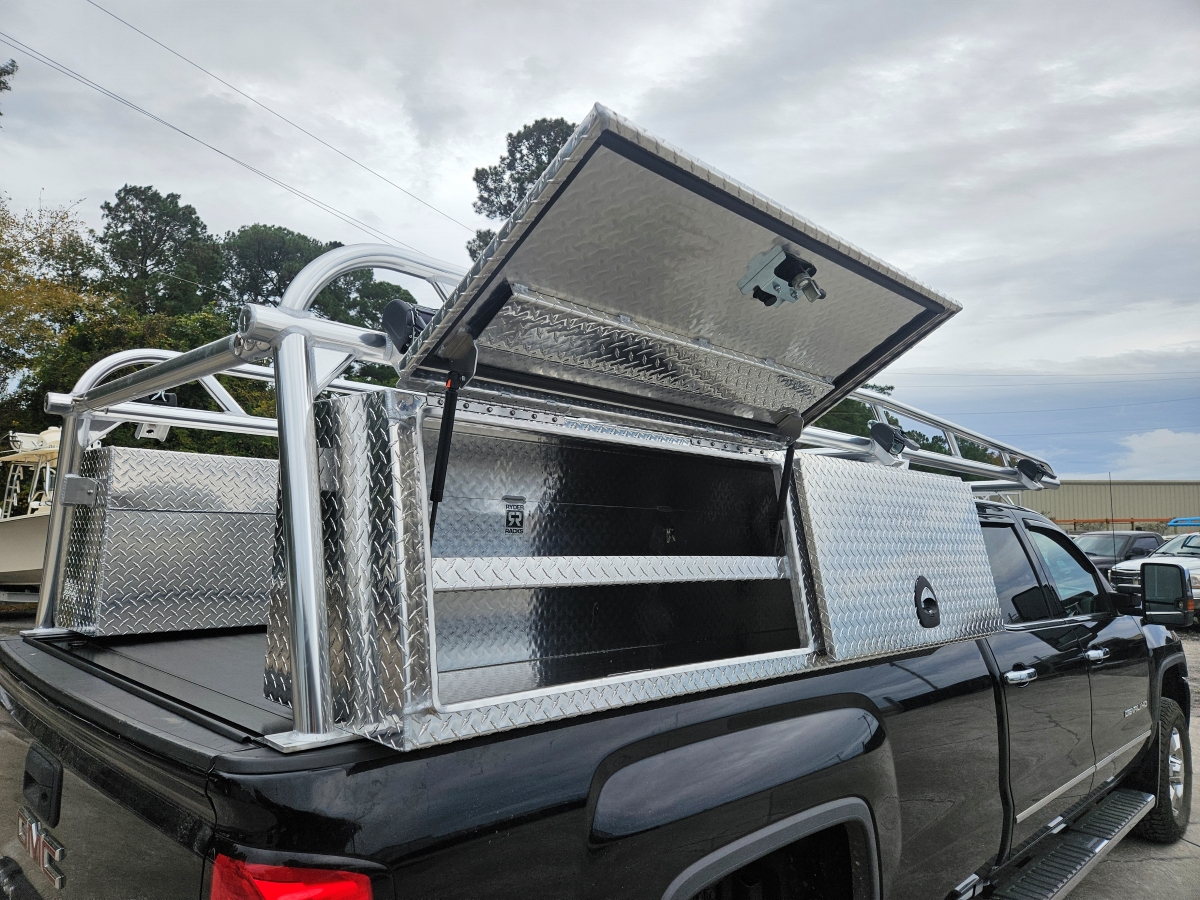 Side profile of black pickup with welded over-cab rack and storage boxes.